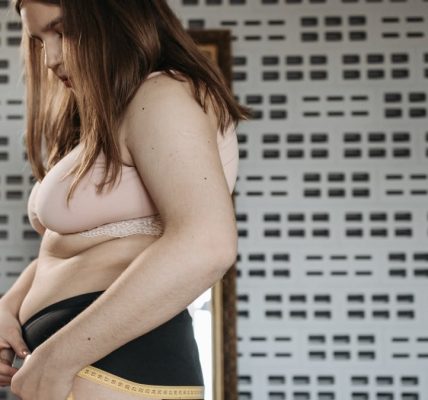 Confident young woman measures her hips in a stylish interior, embracing body positivity.